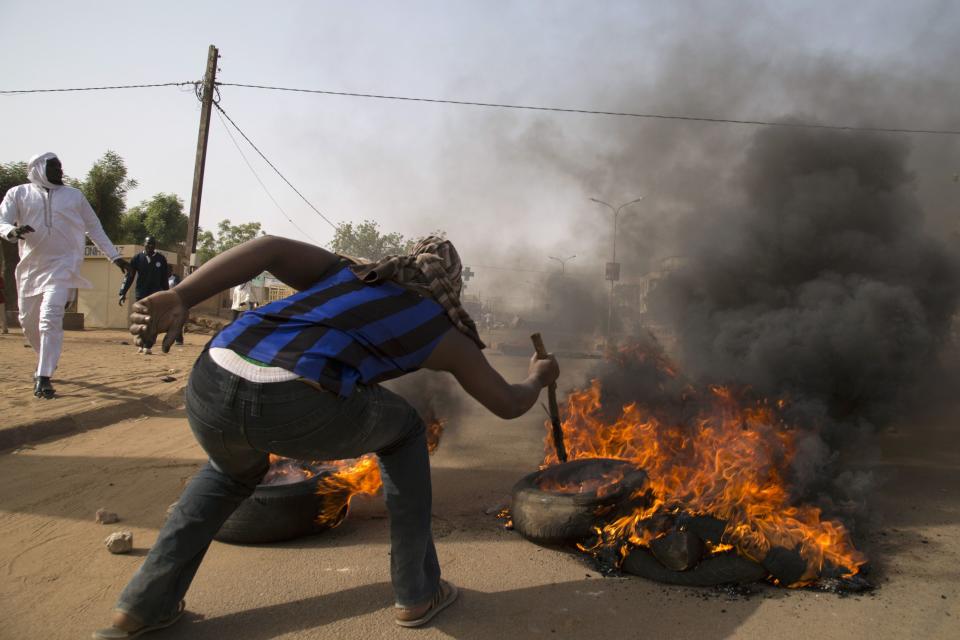 A man burns a tire during a protest against Niger President Mahamadou Issoufou's attendance last week at a Paris rally in support of French satirical weekly Charlie Hebdo, which featured a cartoon of the Prophet Mohammad as the cover of its first edition since an attack by Islamist gunmen, in Niamey January 17, 2015. REUTERS/Tagaza Djibo (NIGER - Tags: CIVIL UNREST POLITICS MEDIA)