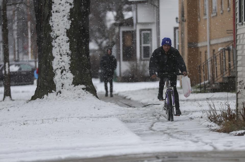 A cyclist rides on a snow-covered sidewalk Wednesday along South Clay Street in Green Bay.