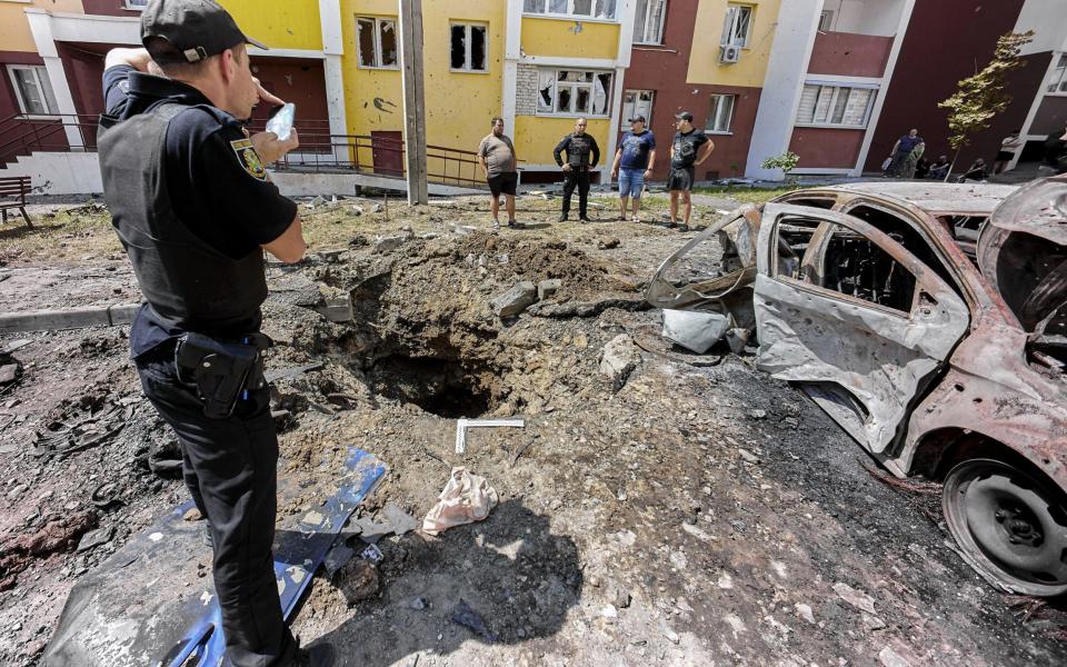 Mandatory Credit: Photo by SERGEY KOZLOV/EPA-EFE/Shutterstock (13001573a) A policeman makes a photo of a destroyed car and a crater following Russian shelling in a residential area of Kharkiv, Ukraine, 26 June 2022. Russian troops increased shellings of Kharkiv last few days. Russian troops on 24 February entered Ukrainian territory, starting a conflict that has provoked destruction and a humanitarian crisis. According to the UNHCR, more than 5.2 million Ukrainians have fled the country and a further seven million people have been internally displaced within Ukraine since. Aftermath of shelling in Kharkiv, Ukraine - 26 Jun 2022  - SERGEY KOZLOV/EPA-EFE/Shutterstock