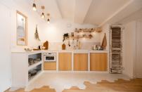 <p>Dans cette <a href="https://www.elle.fr/Deco/News-tendances/10-idees-pour-amenager-une-cuisine-en-L" rel="nofollow noopener" target="_blank" data-ylk="slk:cuisine en L;elm:context_link;itc:0;sec:content-canvas" class="link ">cuisine en L</a>, les volumes sont twistés grâce à un jeu de géométrie. Sur le sol, les carreaux blancs se mêlent au parquet. Sur les meubles, les portes en bois sont structurées par les touches de blanc. Un mix & match rafraîchissant et moderne qui met en lumière la vieille porte patinée.</p><p>Architecte d’intérieur : <a href="https://www.houzz.fr/pro/nomad-eleven/nomad-eleven" rel="nofollow noopener" target="_blank" data-ylk="slk:Nomad Eleven;elm:context_link;itc:0;sec:content-canvas" class="link ">Nomad Eleven</a></p><br>