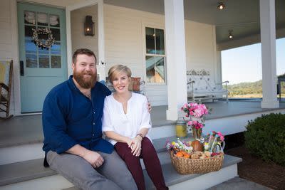 hgtv home town stars erin and ben napier sitting on the covered front porch of a house