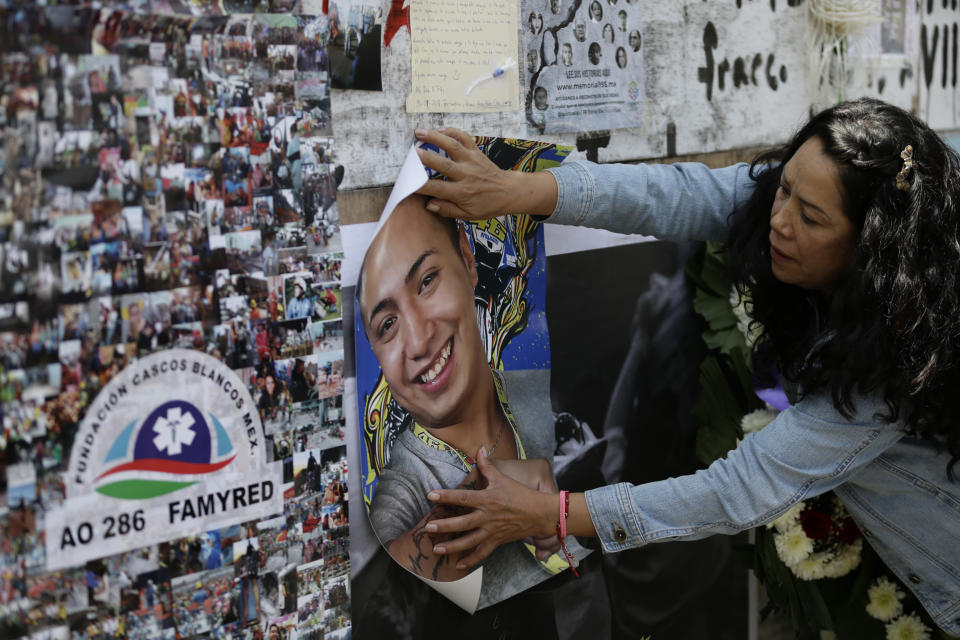 A woman puts up a picture of her family member who died, during a memorial ceremony in front of the site at Alvaro Obregon 286, where 49 were killed when their office building collapsed in last year's 7.1 magnitude earthquake, in Mexico City, Wednesday, Sept. 19, 2018. Across the city, memorials were held at sites where hundreds perished in the Sept. 19, 2017 quake.(AP Photo/Rebecca Blackwell)