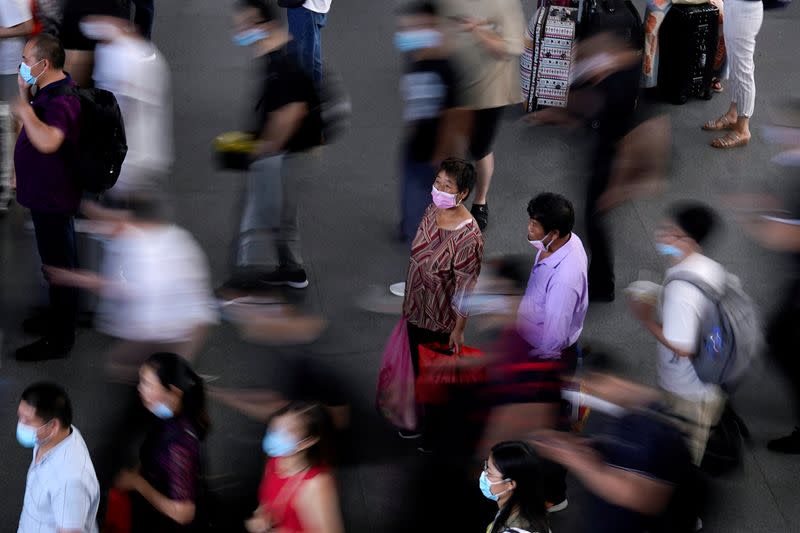 FILE PHOTO: People wearing face masks wait for the train at Suzhou Railway Station in Suzhou