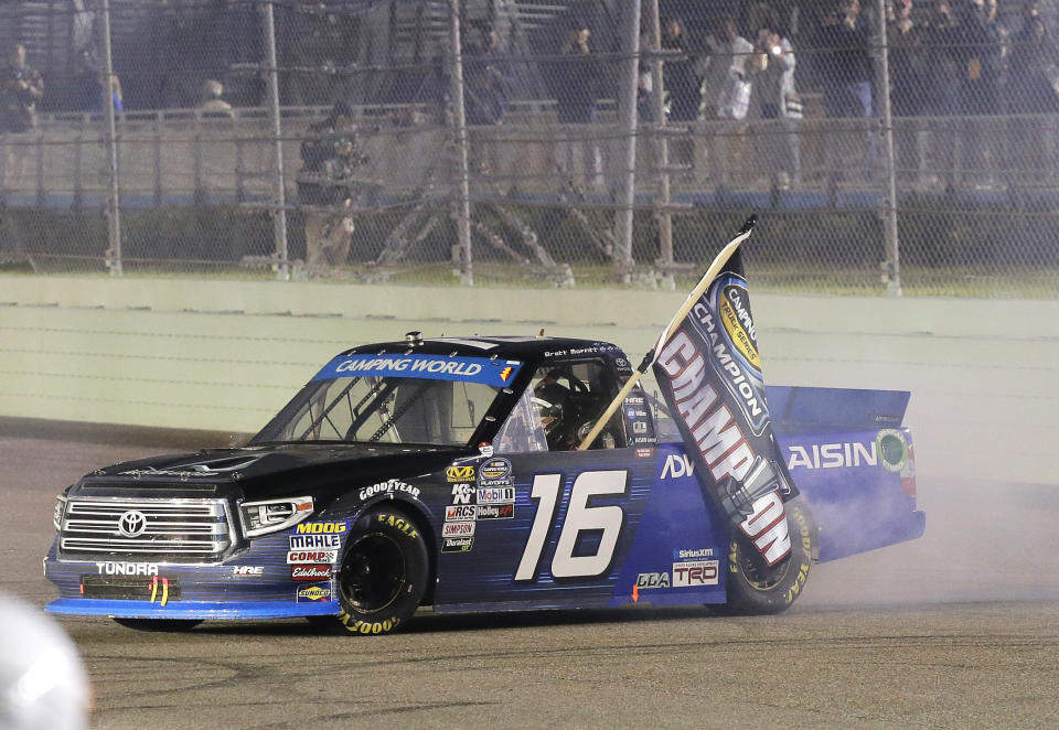 Brett Moffitt drives with a flag after winning the NASCAR Truck Series auto racing season title, at Homestead-Miami Speedway in Homestead, Fla., Friday, Nov. 16, 2018. (AP Photo/Terry Renna)