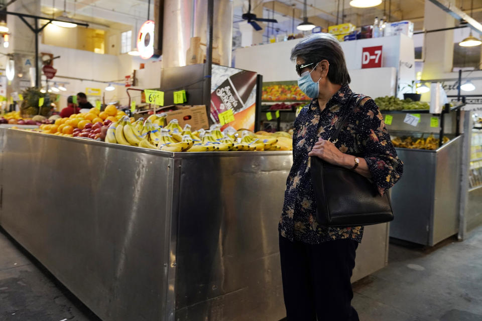 A woman walks past a produce stand at the Grand Central Market, Monday, Nov. 16, 2020, in Los Angeles. Gov. Gavin Newsom announced Monday, Nov. 16, 2020, that due to the rise of COVID-19 cases, some counties have been moved to the state's most restrictive set of rules. The new rules begin Tuesday, Nov. 17. (AP Photo/Marcio Jose Sanchez)