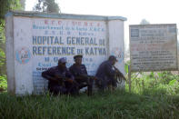 Police shelter behind a hospital sign, as they guard a hospital in Butembo, Congo, on Saturday, April 20, 2019, after militia members attacked an Ebola treatment center in the city’s Katwa district overnight. Violence has deeply complicated efforts to contain what has become the second-deadliest Ebola virus outbreak in history. (AP Photo/Al-Hadji Kudra Maliro)