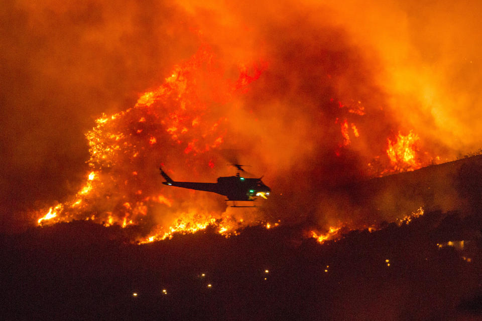 A helicopter prepares to drop water at a wildfire in Yucaipa, Calif., Saturday, Sept. 5, 2020. (AP Photo/Ringo H.W. Chiu)