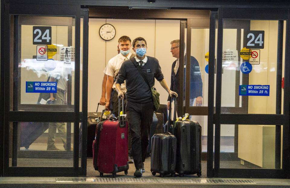 In this Sunday, March 22, 2020 photo, missionaries returning from the Philippines exit the Salt Lake City International Airport. Sen. Mitt Romney and Utah state leaders are criticizing a large gathering of family and friends who went to the airport to welcome the missionaries home when people are supposed to be keeping their distance from one another to prevent more spread of the coronavirus. (Rick Egan/The Salt Lake Tribune via AP)