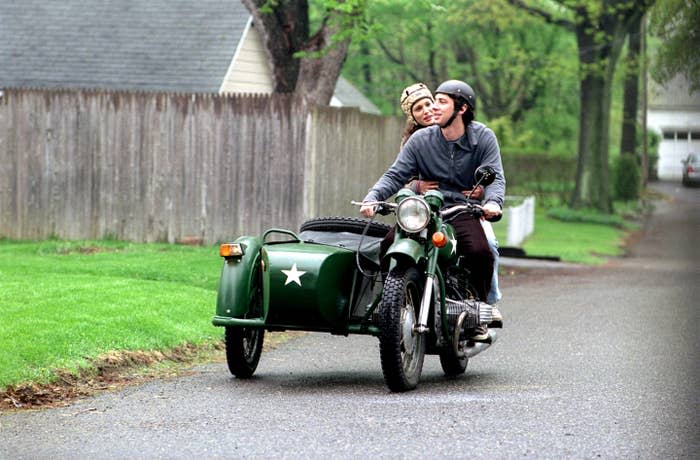 couple riding on a bike that has a side cart