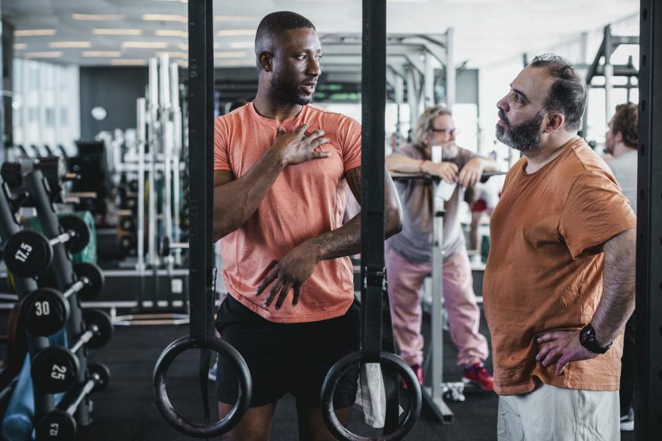 male fitness instructor explaining man in health club