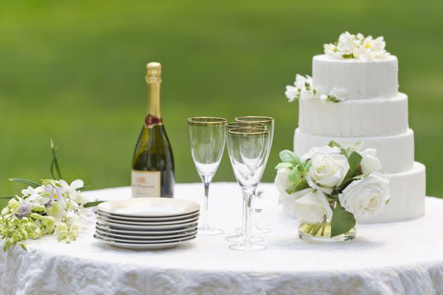 <p><br/>Tetra Images/ Getty Images</p> USA, New York State, Old Westbury, Table with champagne bottle and wedding cake - stock photo