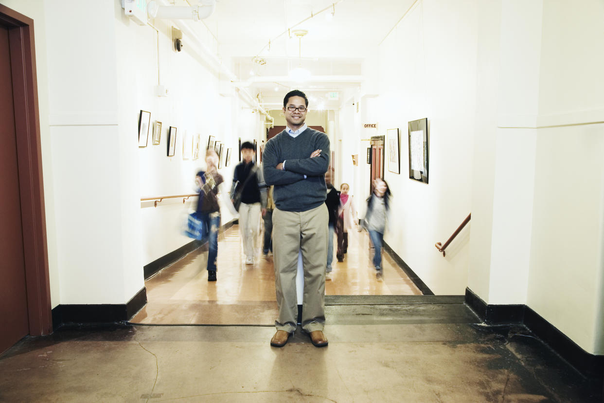 Teacher and students (9-13) in school corridor (focus on teacher)