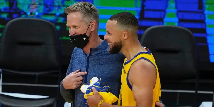 Steve Kerr puts his arm around Stephen Curry as they laugh after a game in 2021.