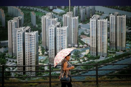 A woman walks past an advertisement promoting an apartment complex which is currently under construction in Yongin, South Korea, August 24, 2016. REUTERS/Kim Hong-Ji