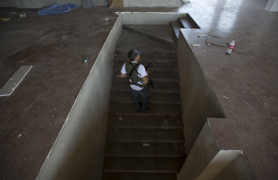 A man belonging to the Self-Defense Council of Michoacan, (CAM), walks up the stairs of a building in the town of Nueva Italia, Mexico, Monday, Jan. 13, 2014. A day earlier the self-defenses encountered resistance as they tried to rid the town of the Knights Templar drug cartel while the government announced today that federal forces will take over security in a large swath of a western Mexico that has been hard hit by violence. (AP Photo/Eduardo Verdugo)