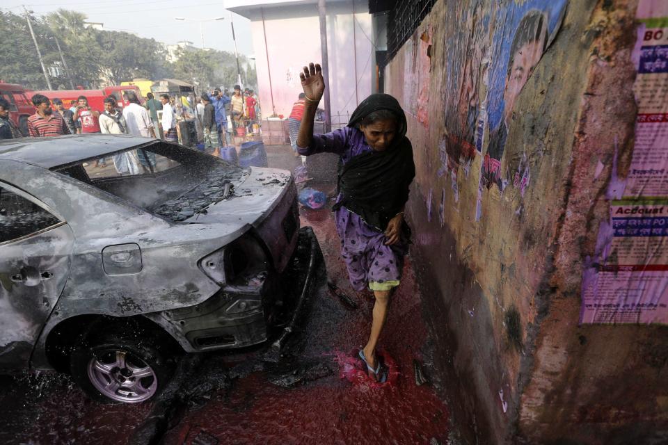 A woman steps on colored water thrown to control fire by a police van, after clashes between Bangladesh's Jamaat-e-Islami party activists and police, in Dhaka