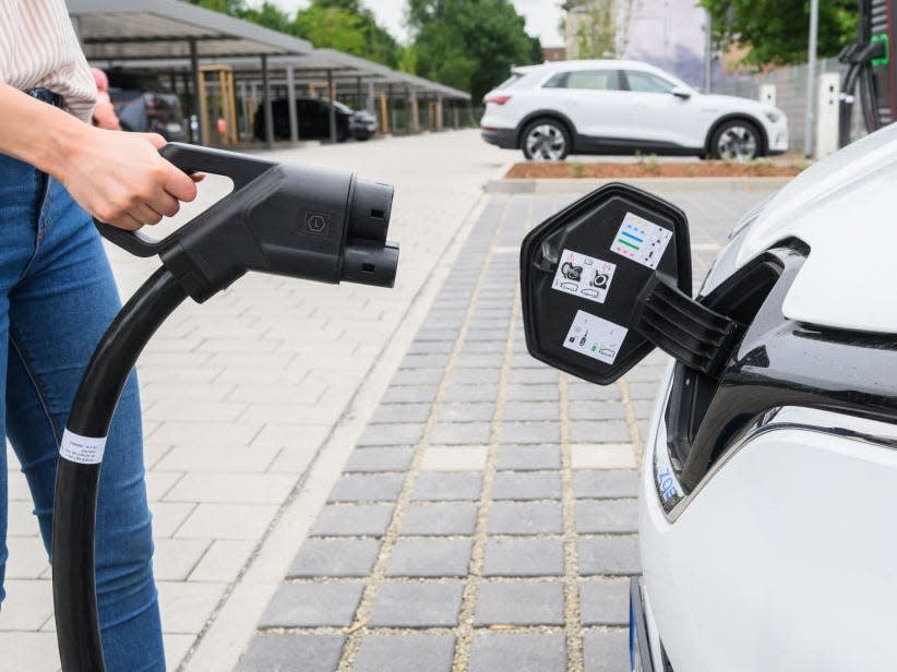 01 July 2022, Lower Saxony, Hanover: An Enercity employee stands with a charging cable for a Renault Zoe electric car at a fast-charging point in a new charging park.