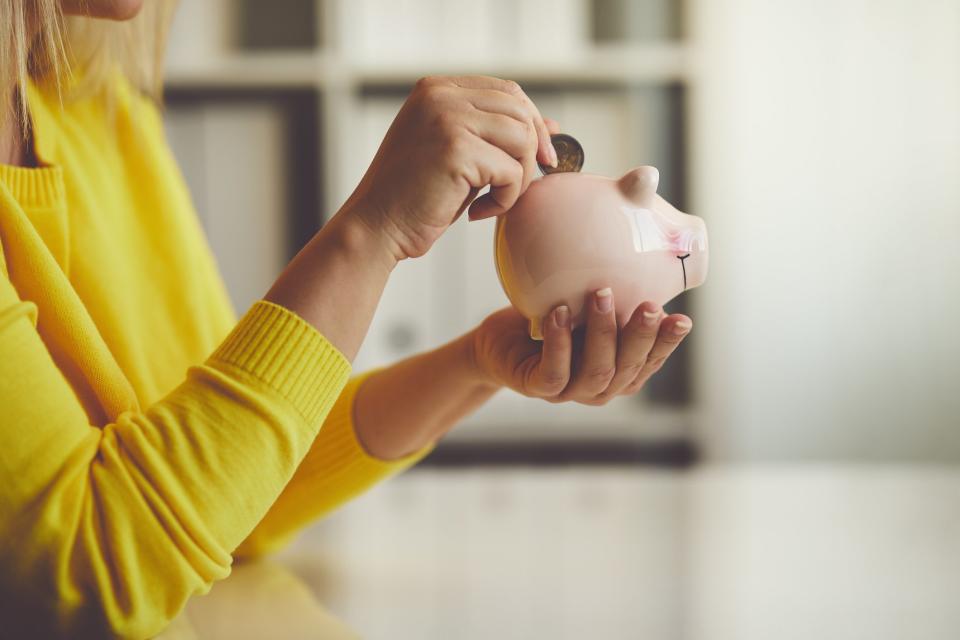 Woman putting coin in piggy bank.