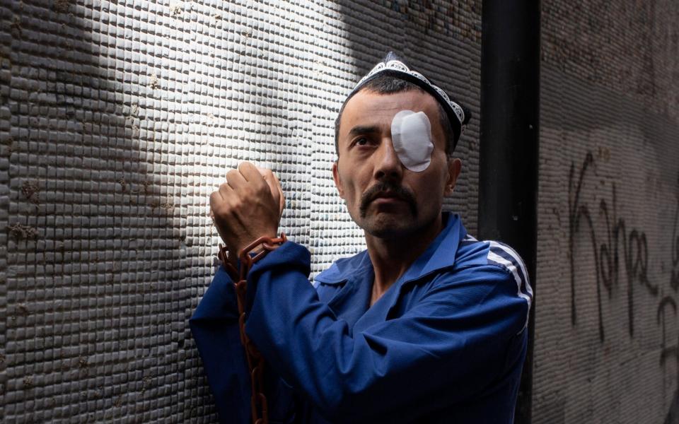 A Uighur activist wears plastic chains and an imitation prison uniform ahead of a demonstration outside the Chinese embassy in Istanbul - Sam Tarling for The Telegraph 