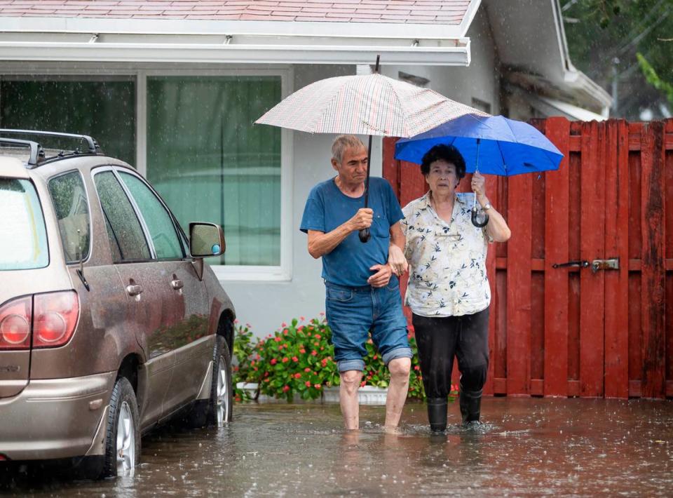 People stand outside in flooded waters in the Edgewood neighborhood on Thursday, April 13, 2023, in Fort Lauderdale, Fla. A torrential downpour severely flooded streets partially submerging houses and cars across South Florida.