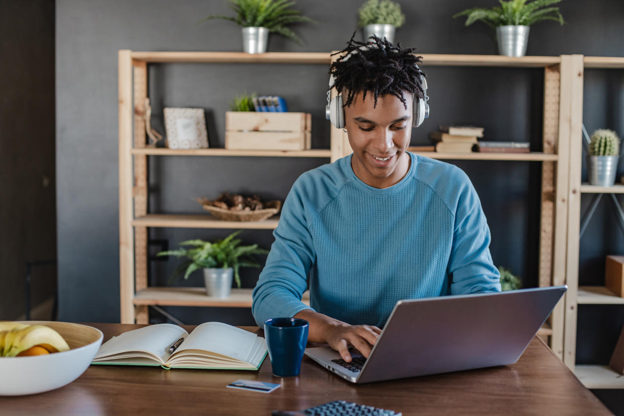 A young man is working from home on his laptop