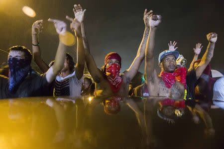 Protesters gesture as they stand in the street in defiance of a midnight curfew meant to stem ongoing demonstrations in reaction to the shooting of Michael Brown in Ferguson, Missouri August 17, 2014. REUTERS/Lucas Jackson