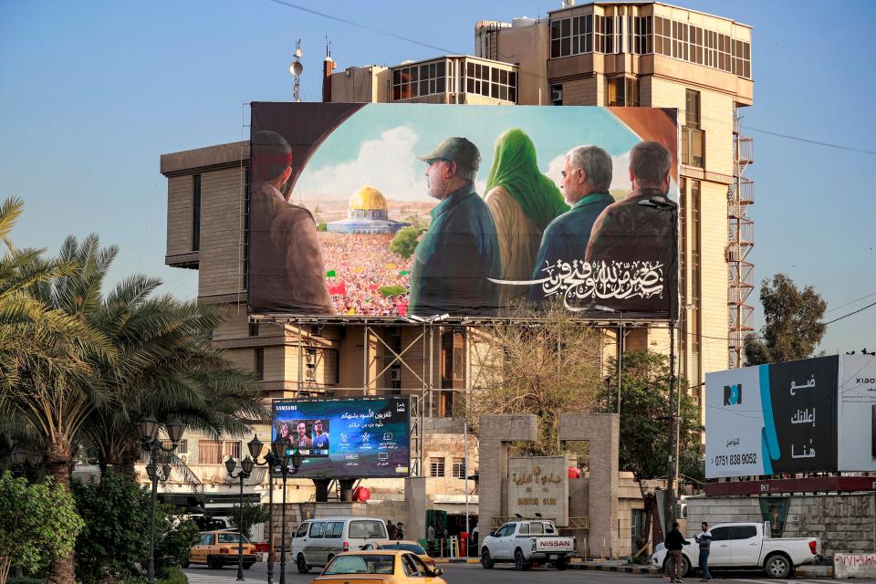 Vehicles drive along al-Firdous square in Baghdad on March 9, 2023 with a prominent billboard showing the slain head of Iran's Islamic Revolutionary Guard Corps (IRGC)'s "Quds Force" Qasem Soleimani (2nd-R) and the Iraqi Hashed al-Shaabi (Popular Mobilisation) forces commander Abu Mahdi al-Muhandis (2nd-L) with a figure wearing green and others looking towards the Dome of the Rock mosque in Jerusalem.