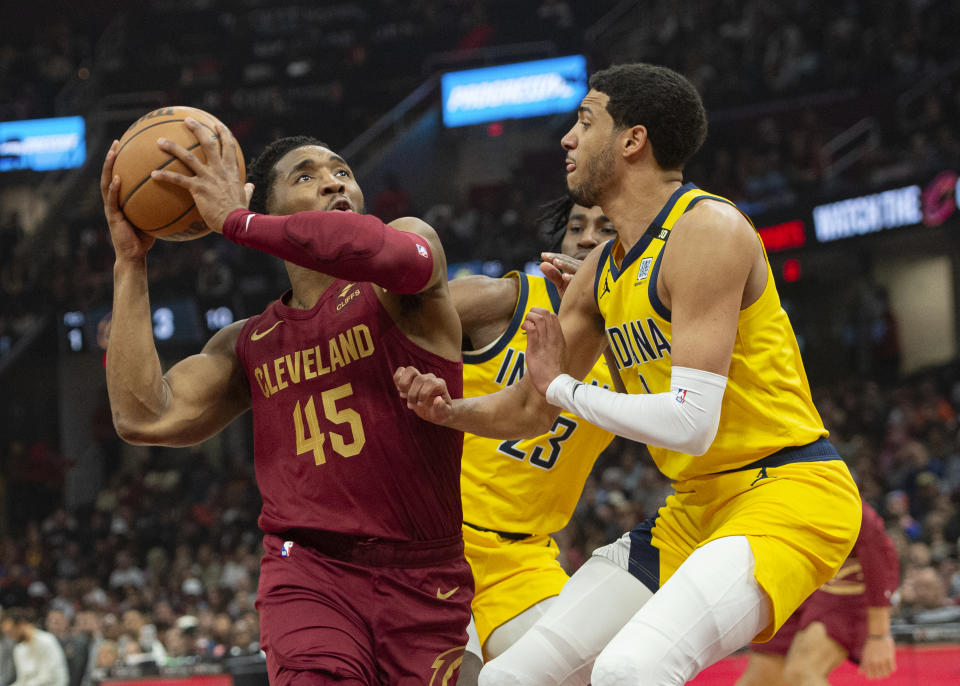 Cleveland Cavaliers' Donovan Mitchell (45) looks to shoot as Indiana Pacers' Tyrese Haliburton, right, defends during the first half of an NBA basketball game in Cleveland, Friday, April 12, 2024. (AP Photo/Phil Long)