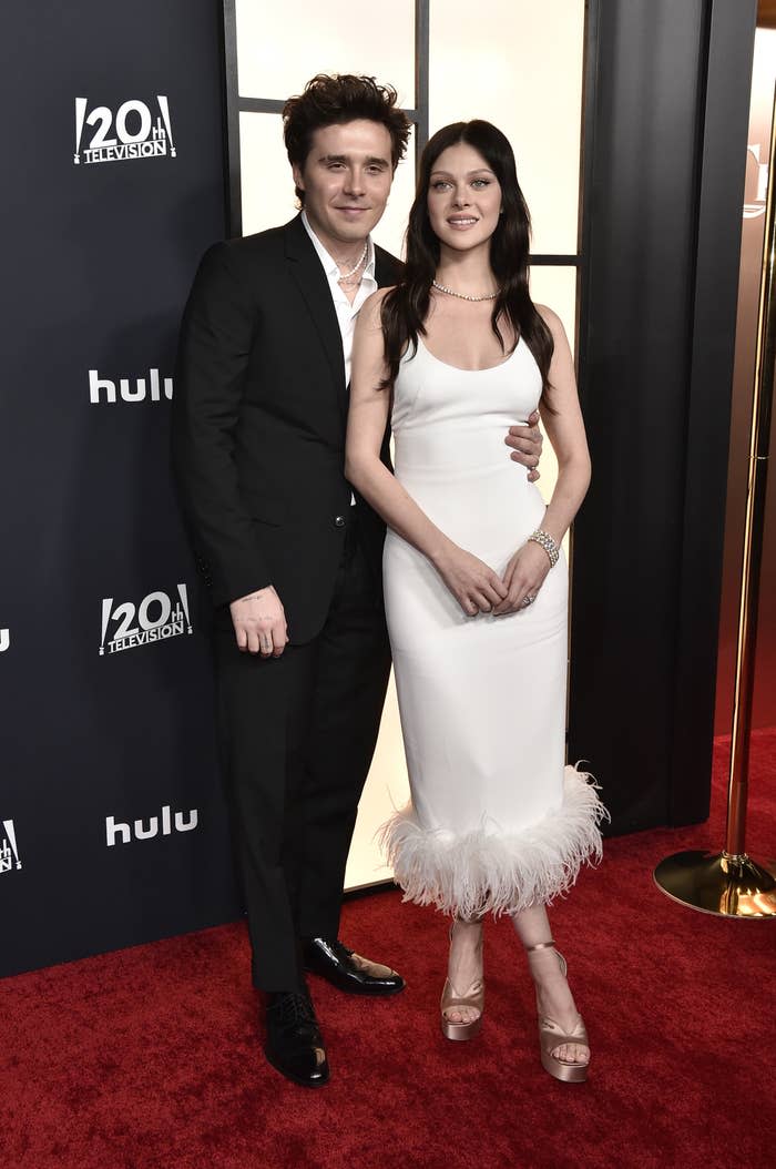 Brooklyn, on the left, with his arm around Nicola as they smile for photographers on the red carpet