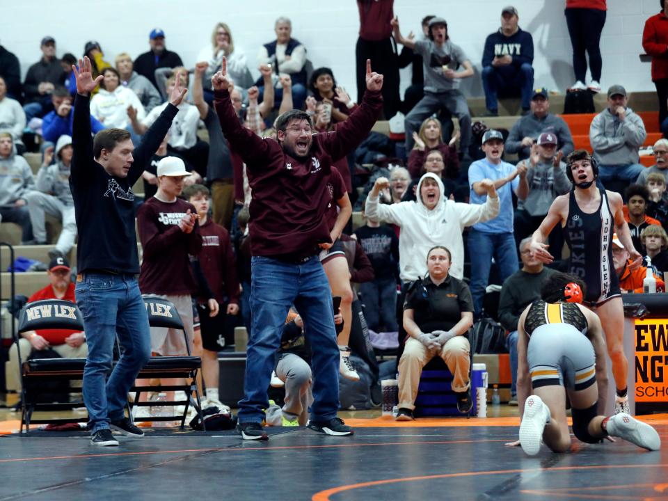 John Glenn's Dominic Bates, far right, celebrates with coaches and fans after an escape in double overtime during his finals match with New Lexington's Mason Rider at the Muskingum Valley League Tournament in New Lexington. Bates held on for a 6-5 win in double overtime.