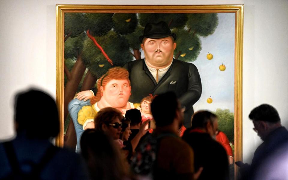 Visitors look at Botero's painting "Una Familia."