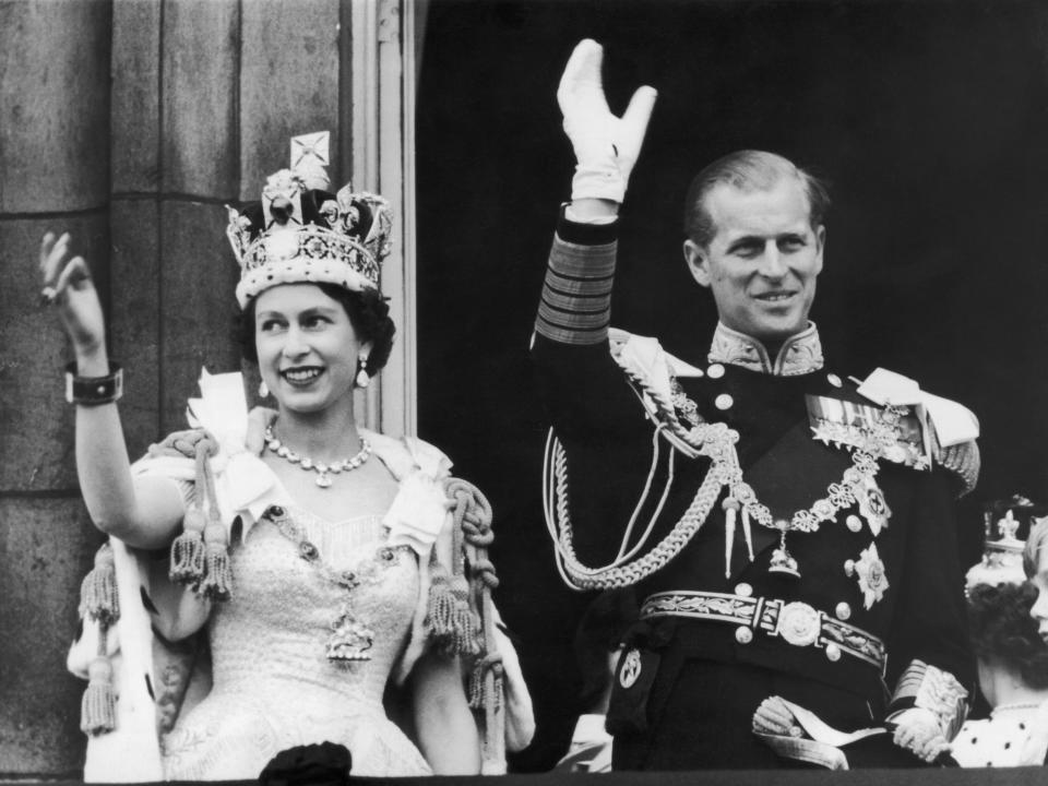 Queen Elizabeth II and the Duke of Edinburgh wave at the crowds from the balcony at Buckingham Palace after Elizabeth's coronation on June 2, 1953