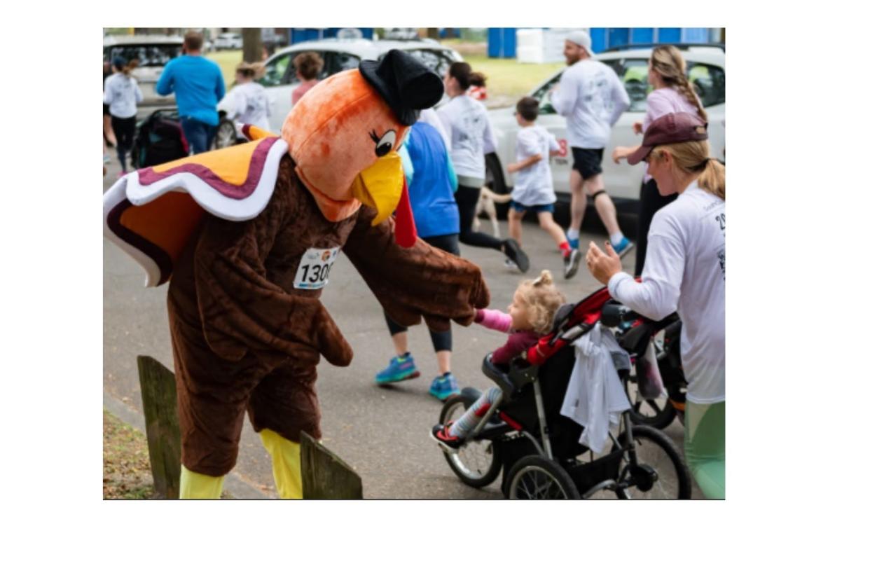 United Way of the Coastal Empire's Turkey mascot greets a young trotter at a previous Turkey Trot event. The mascot will be on hand for the annual event taking place on Thanksgiving morning Nov. 23, 2023.