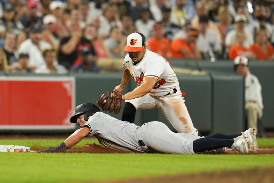 Baltimore Orioles third baseman Ramon Urias, top, tags out New York Yankees' Anthony Volpe trying to move to third base on a fielder's choice groundout by Gleyber Torres during the seventh inning of a baseball game, Saturday, July 29, 2023, in Baltimore. (AP Photo/Julio Cortez)