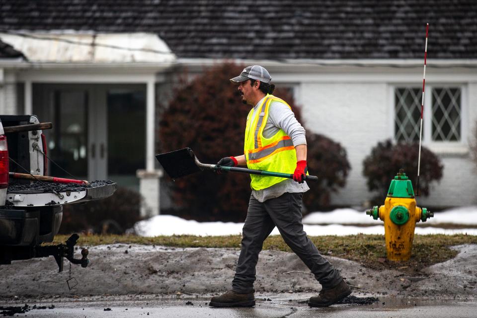 A worker fixes potholes on Fleur Drive in Des Moines.