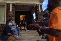 Demetrius Mingo, right, an outreach worker with the Target Area Development Corporation, a nonprofit that addresses stubborn local problems, talks with residents while making rounds looking to mediate conflicts in the Auburn Gresham neighborhood in Chicago, Saturday, Aug. 22, 2020. The group has also walked the streets to warn one segment of the population, victims and perpetrators of gun violence, of the dangers of a virus they could unwittingly pass on to their families. (AP Photo/David Goldman)