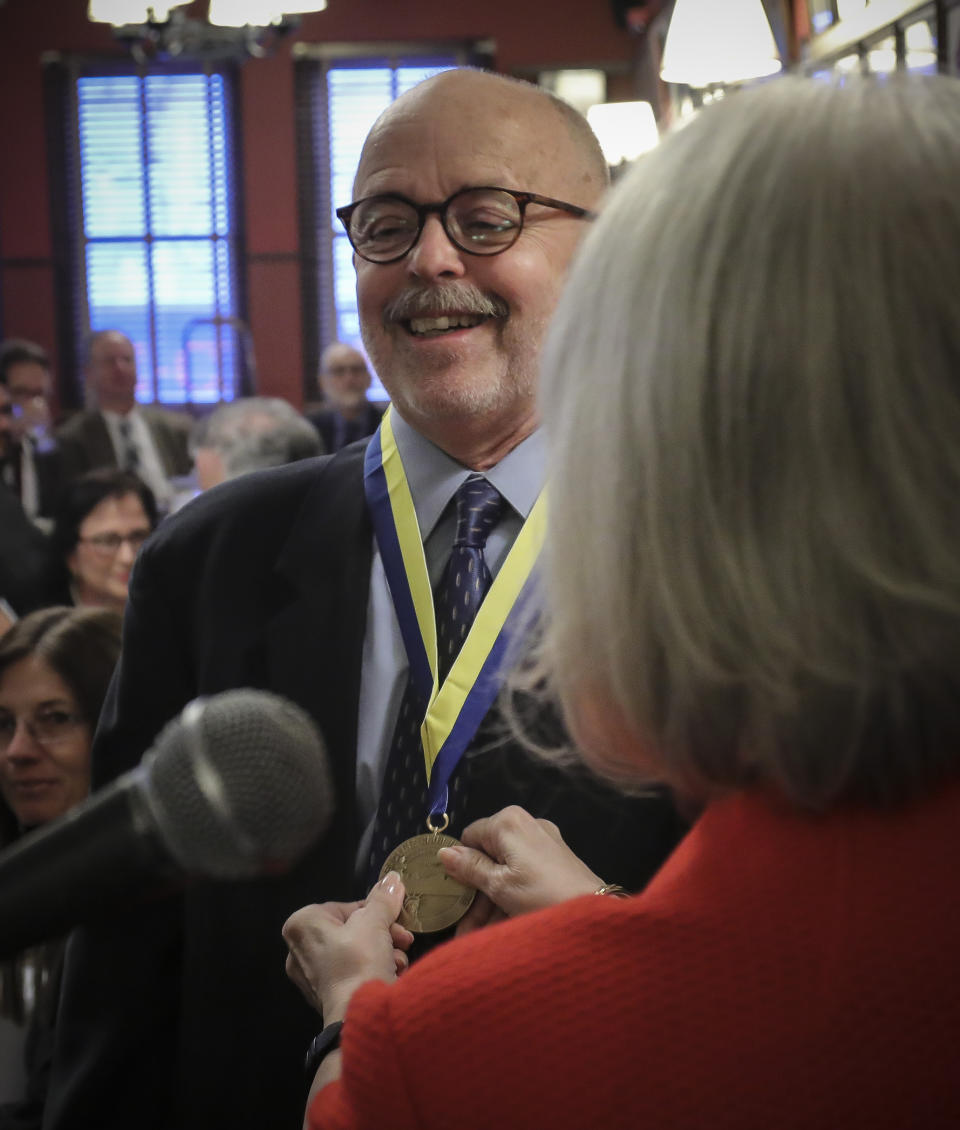 Associated Press photojournalist and Pulitzer Prize winner Richard Drew is inducted into The Deadline Club Hall of Fame, as Deadline club president Claire Regan presents him with the medal for life achievement, Thursday Nov. 21, 2019, in New York. Drew, a staff photographer for AP in New York known for taking the The Falling Man photograph during the Sept. 11, 2001 attacks, is the first photojournalist to be inducted. (AP Photo/Bebeto Matthews)