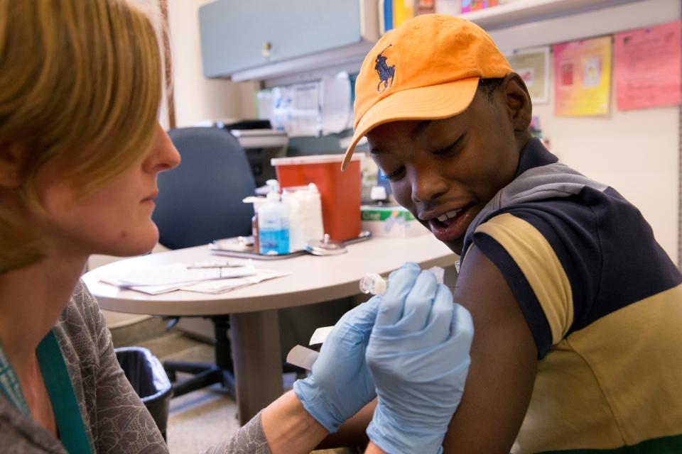Cameron Wilson, 11, watches as public health nurse Debra Mortwedt administers a measles vaccine at the Southside Health Center in Milwaukee in 2015. Wisconsin law requires that children be immunized against a range of illnesses, such as mumps, measles and pertussis, in order to attend school and child care settings.