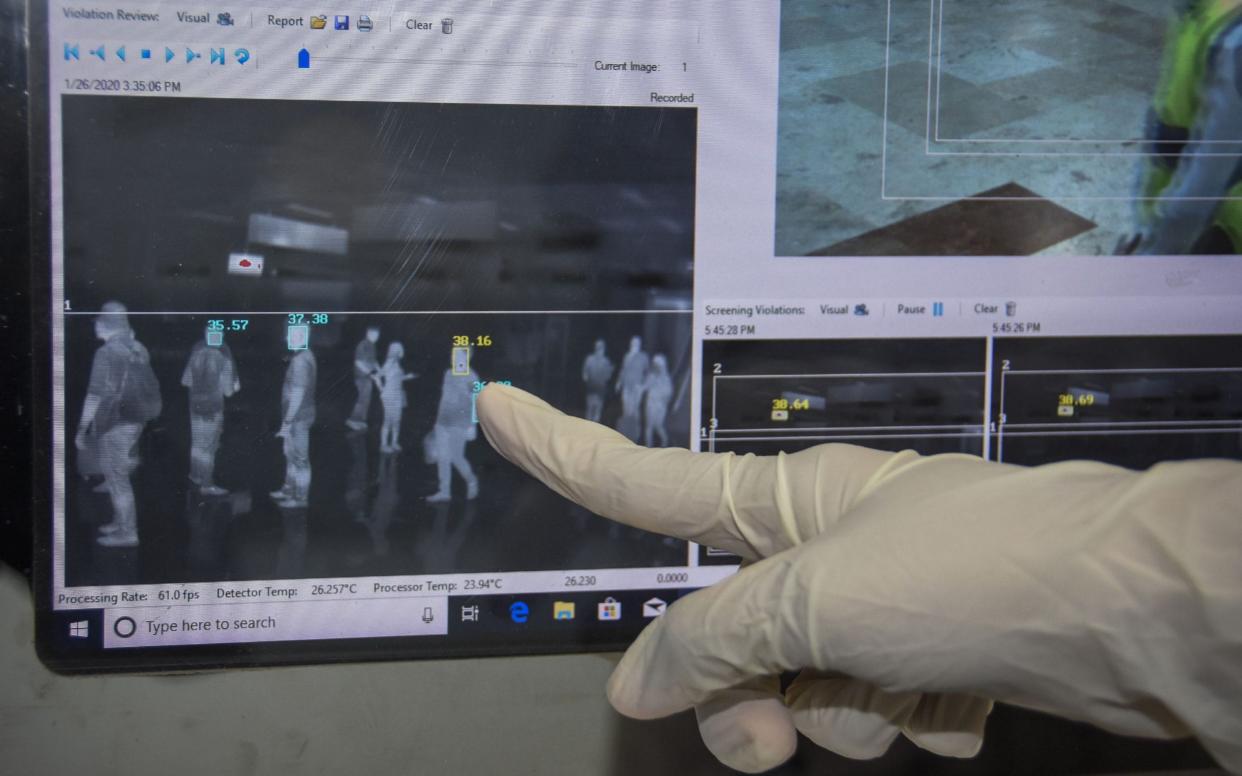 An Indonesian health officer point at a thermal scanner used to screen airline passengers for symptoms of the deadly virus  - AFP