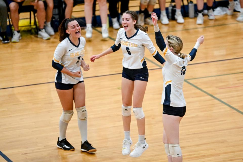 From left, Grand Ledge's Noemi Malvestio, Kylie Goodman and Annie Grew celebrate a point against DeWitt in the second set during the district final match on Thursday, Nov. 3, 2022, at Grand Ledge High School.