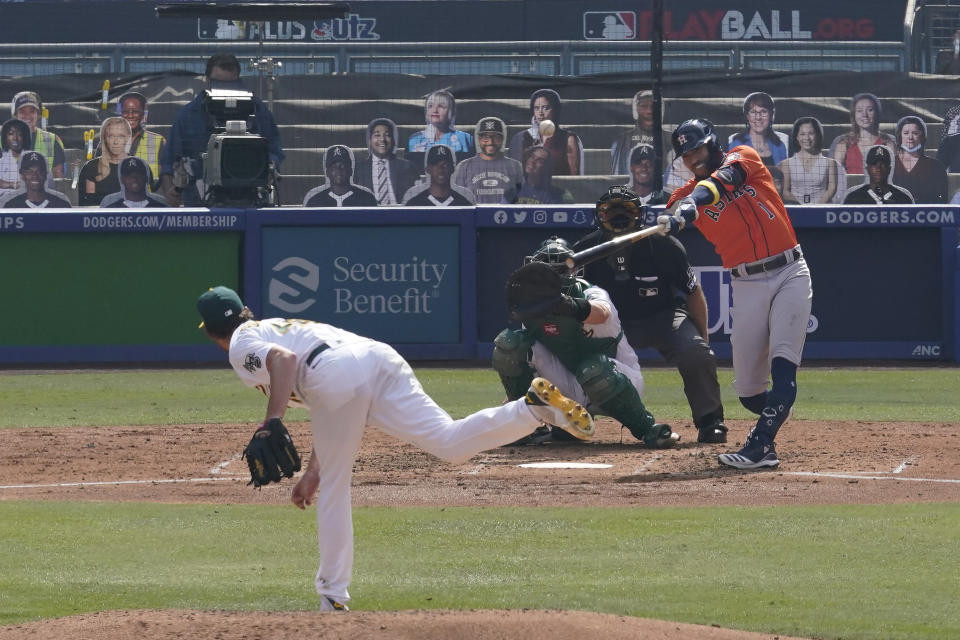 Houston Astros' Carlos Correa (1) hits a two-run home run off of Oakland Athletics pitcher Chris Bassitt, left, during the fourth inning of Game 1 of a baseball American League Division Series in Los Angeles, Monday, Oct. 5, 2020. (AP Photo/Marcio Jose Sanchez)