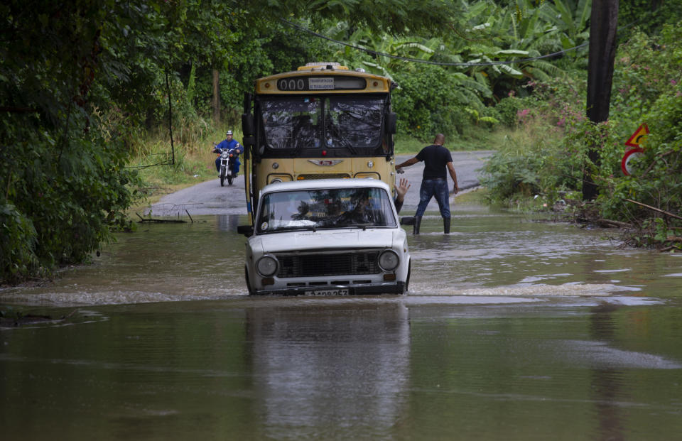 Vehículos trata de avanzar por una vía inundada por lluvias torrenciales, en La Habana, Cuba, el miércoles 13 diciembre de 2023. (AP Foto/Ismael Francisco)