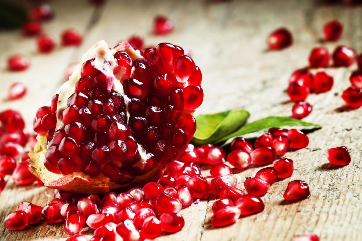 pomegranates with ruby red beans on old wooden table