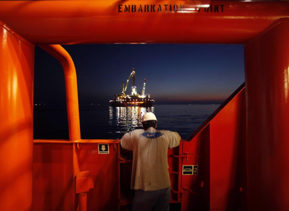 FILE - Wilson Ruiz, a crew member of the Joe Griffin, looks out at the oil slick as a containment vessel onboard positioned near the Q4000, background center, being lowered over the oil leak, at the site of the BP Deepwater Horizon offshore oil rig collapse in the Gulf of Mexico on May 6, 2010. A new National Academy of Science study says that 13 years after a massive BP oil spill fouled the Gulf of Mexico, regulators and industry have reduced some risks in deep water exploration in the gulf but some troublesome safety issues persist. (AP Photo/Gerald Herbert, File)