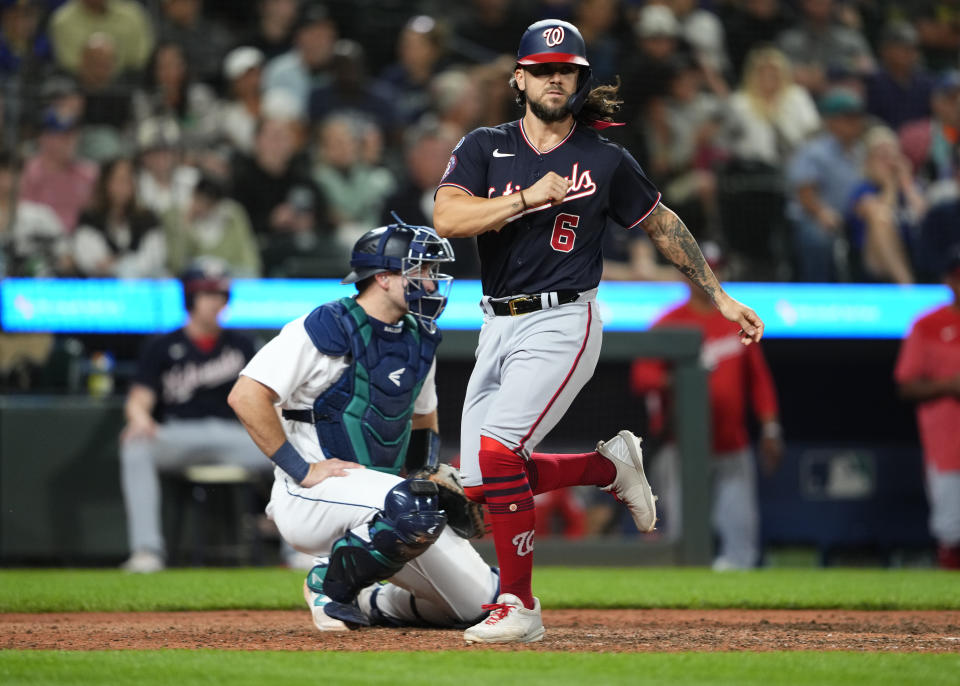 Washington Nationals' Kyle Finnegan scores on a double by Lane Thomas, next to Seattle Mariners catcher Cal Raleigh during the 11th inning of a baseball game Tuesday, June 27, 2023, in Seattle. The Nationals won 7-4. (AP Photo/Lindsey Wasson)