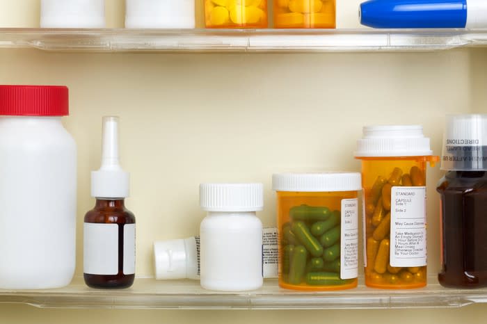 Bottles of pills on two shelves inside a medicine cabinet.