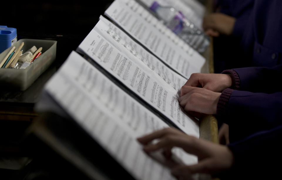 In this Wednesday, Jan. 22, 2014 photo, members of the first female choir follow this music from sheets during rehearsals in Canterbury Cathedral, Canterbury, England, prior to their debut on Jan. 25. The pure, high voices of the choir soar toward the vaulted ceiling of Canterbury Cathedral as they have for more than 1,000 years. Just one thing is different _ these young choristers in their purple cassocks are girls, and their public debut at Evensong on Saturday will end centuries of all-male tradition. Canterbury is not the first British cathedral to set up a girls' choir, but as mother church of the 80 million-strong Anglican Communion _ one struggling with the role of women in its ranks _ its move has special resonance. (AP Photo/Alastair Grant)