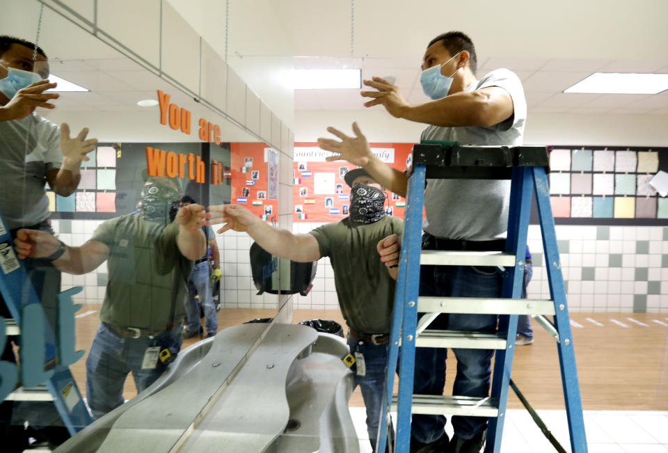 Richardson Independent School District workers Rogelio Ponciano, right, and Matt Attaway install a plexiglass barrier for the sink in the student restroom at Bukhair Elementary School in Dallas, Wednesday, July 15, 2020. Texas Education Commissioner Mike Morath told the state Board of Education on Tuesday that the annual State of Texas Assessments of Academic Readiness, also known as STAAR, will return in the 2020-2021 school year. (AP Photo/LM Otero)