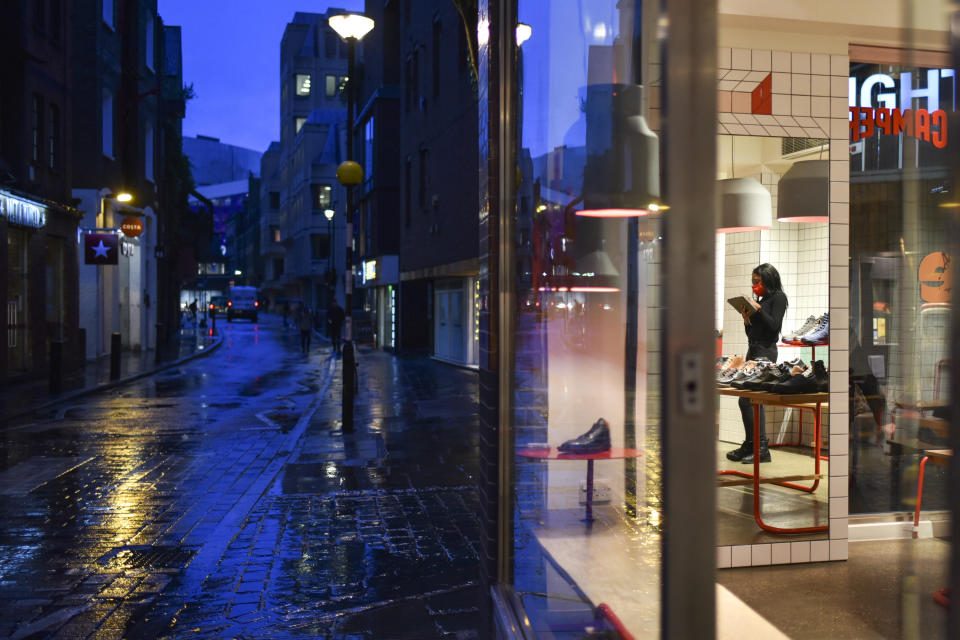 A member of staff wears a face mask as she is reflected into a mirror of a retail shop in Covent Garden, in London, Wednesday, Dec. 16, 2020. London and some of its surrounding areas will be placed under Britain's highest level of coronavirus restrictions beginning at 00:01 local time on today as infections rise rapidly in the capital. Under Tier 3 restrictions, the toughest level in England's three-tier system, people can't socialize indoors, and bars, pubs and restaurants must close except for takeout.(AP Photo/Alberto Pezzali)