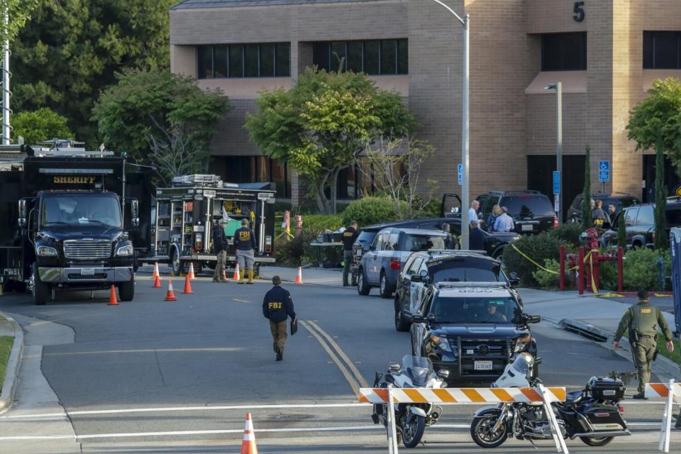 Investigators outside a multi-story brick building.